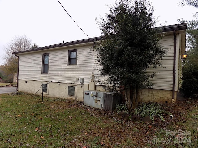 back of property featuring central AC unit and a yard