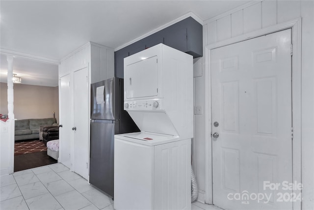 washroom with crown molding and stacked washer and clothes dryer