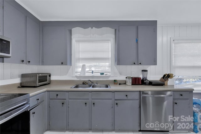 kitchen with stainless steel appliances, a wealth of natural light, gray cabinetry, and sink