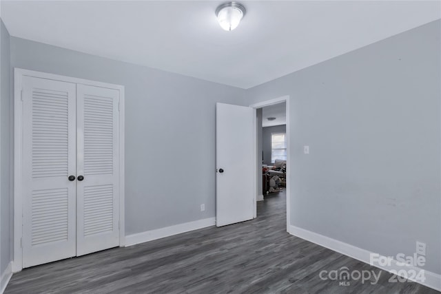 unfurnished bedroom with a closet and dark wood-type flooring