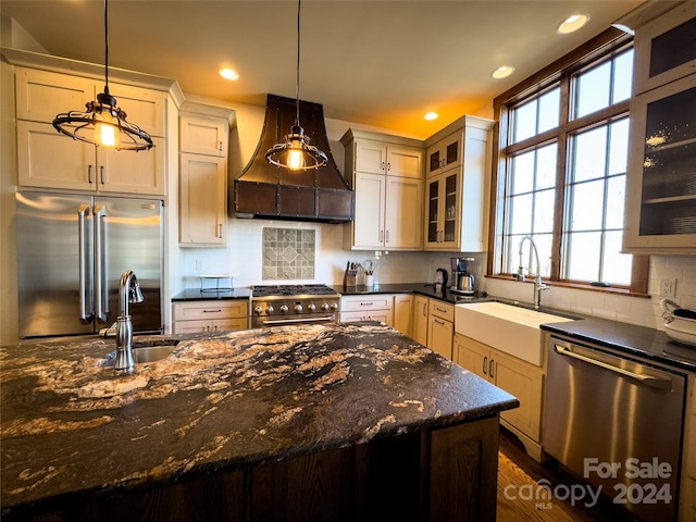 kitchen with sink, decorative light fixtures, high quality appliances, and custom exhaust hood