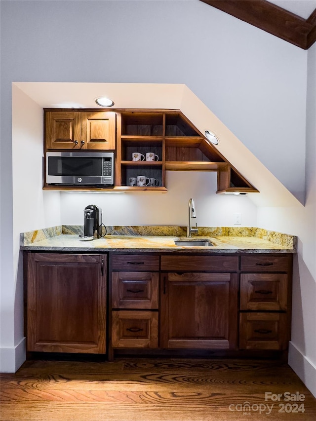 bar with dark hardwood / wood-style floors, lofted ceiling with beams, light stone counters, and sink