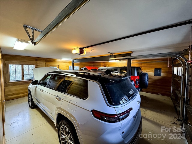 garage with a garage door opener and wood walls