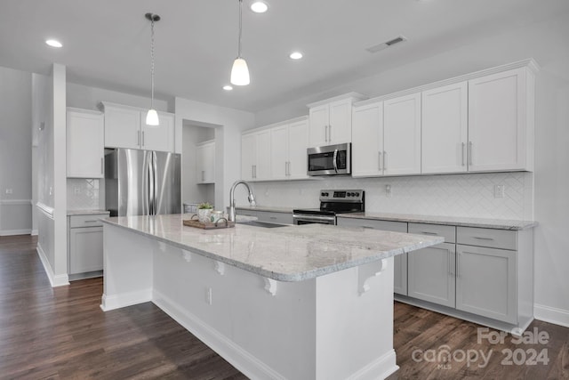 kitchen with a center island with sink, hanging light fixtures, sink, appliances with stainless steel finishes, and dark hardwood / wood-style flooring