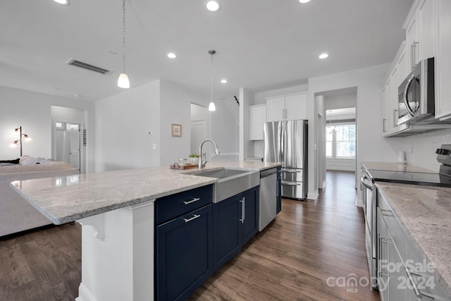 kitchen featuring dark wood-type flooring, white cabinets, blue cabinetry, an island with sink, and appliances with stainless steel finishes