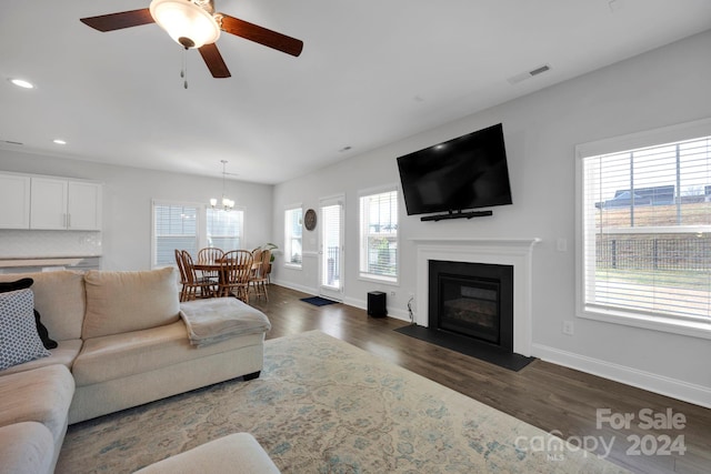 living room with plenty of natural light, dark wood-type flooring, and ceiling fan with notable chandelier