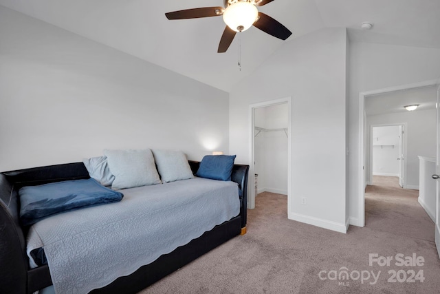 carpeted bedroom with a walk in closet, a closet, vaulted ceiling, and ceiling fan