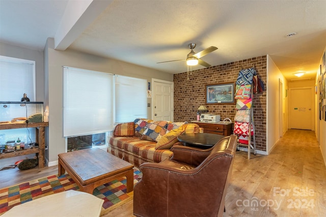 living room featuring ceiling fan, brick wall, and light hardwood / wood-style flooring