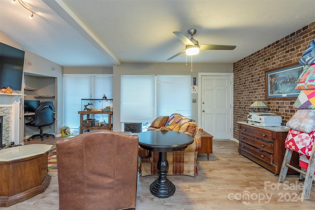 interior space with light wood-type flooring, ceiling fan, and brick wall