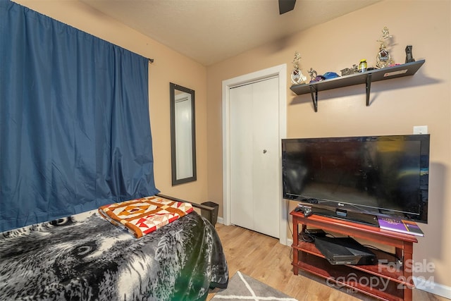 bedroom featuring a textured ceiling, light hardwood / wood-style flooring, a closet, and ceiling fan