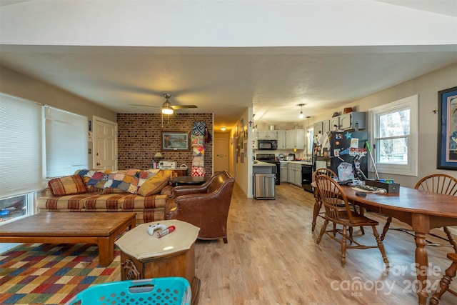 living room with light hardwood / wood-style flooring, ceiling fan, and brick wall