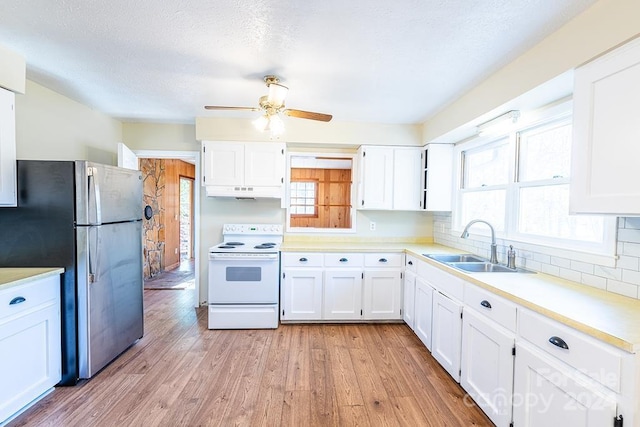 kitchen with sink, white range with electric stovetop, stainless steel fridge, white cabinets, and light wood-type flooring