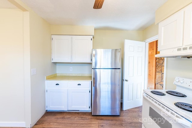 kitchen with dark wood-type flooring, white electric range, range hood, white cabinetry, and stainless steel refrigerator