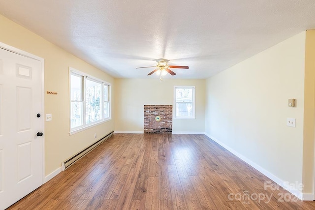 unfurnished living room featuring ceiling fan, hardwood / wood-style floors, a baseboard radiator, and a textured ceiling