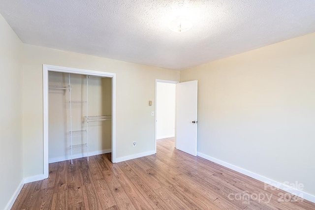 unfurnished bedroom featuring a closet, a textured ceiling, and light hardwood / wood-style flooring