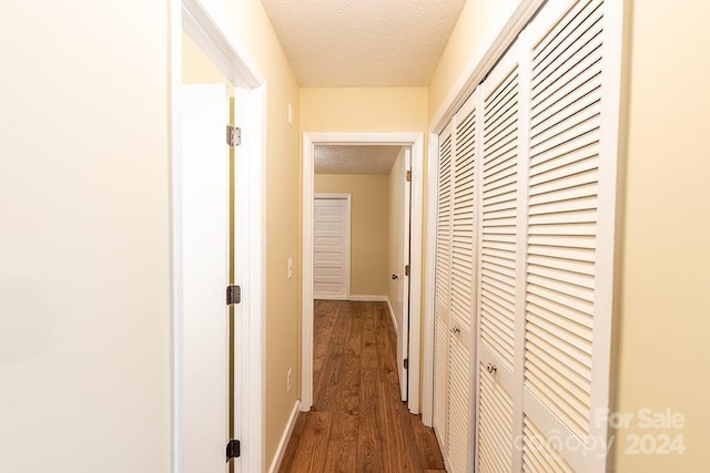 hallway with dark hardwood / wood-style floors and a textured ceiling