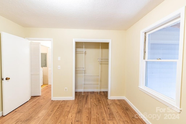 unfurnished bedroom with a closet, light hardwood / wood-style flooring, and a textured ceiling