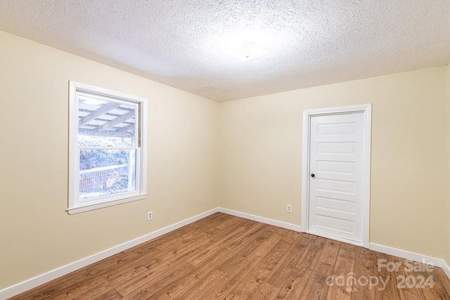 unfurnished room with hardwood / wood-style floors and a textured ceiling