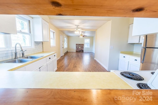 kitchen with decorative backsplash, white range oven, sink, white cabinets, and light hardwood / wood-style floors