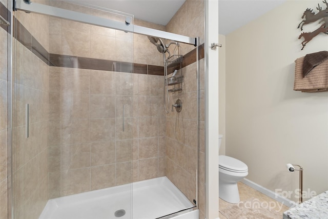 bathroom featuring tile patterned floors, toilet, and a shower with door