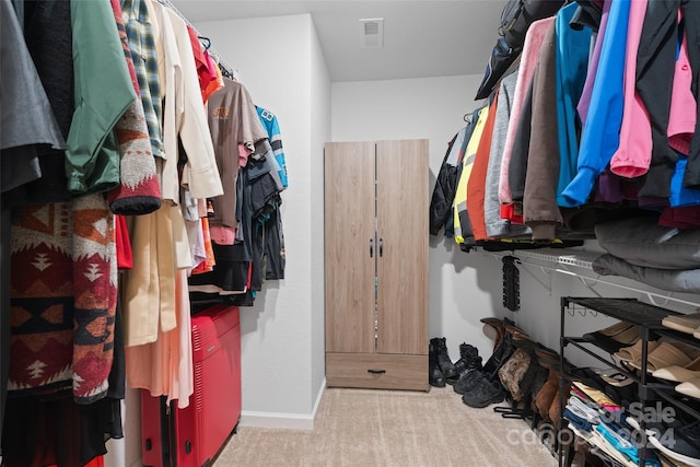 walk in closet with light carpet