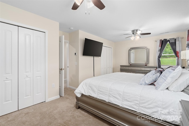 carpeted bedroom with multiple closets and ceiling fan