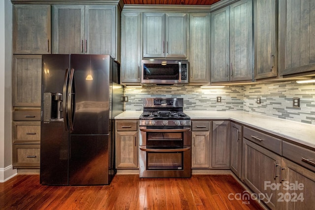 kitchen with light stone countertops, backsplash, stainless steel appliances, and dark wood-type flooring