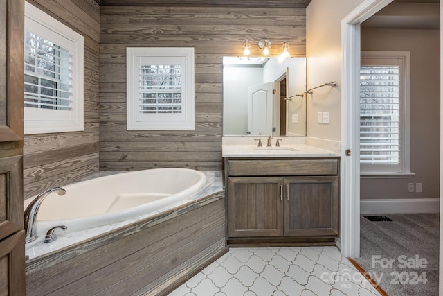 bathroom with a tub to relax in, wooden walls, tile patterned flooring, and vanity