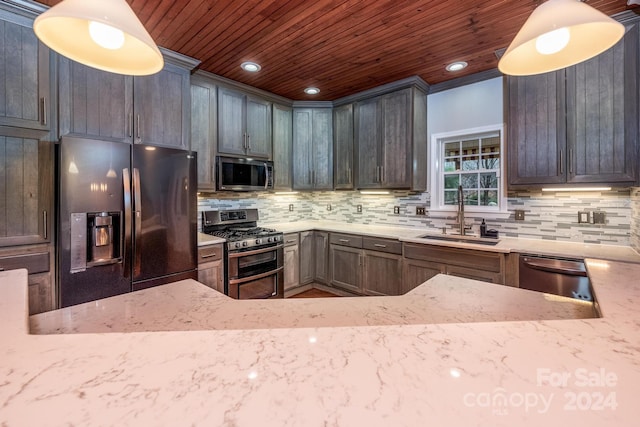 kitchen with decorative light fixtures, light stone counters, sink, and appliances with stainless steel finishes