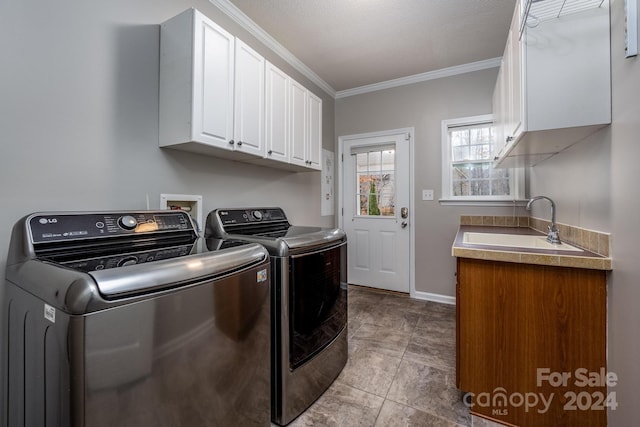 clothes washing area featuring washer and clothes dryer, cabinets, crown molding, sink, and a textured ceiling