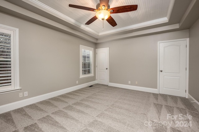 carpeted spare room with a tray ceiling, ceiling fan, wooden ceiling, and ornamental molding