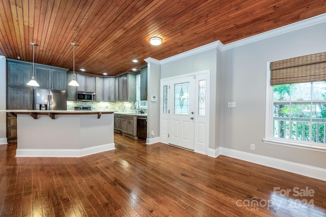 kitchen with dark hardwood / wood-style floors, ornamental molding, decorative light fixtures, a kitchen island, and stainless steel appliances