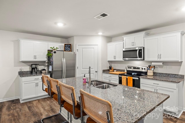 kitchen with stone counters, sink, dark wood-type flooring, stainless steel appliances, and white cabinets