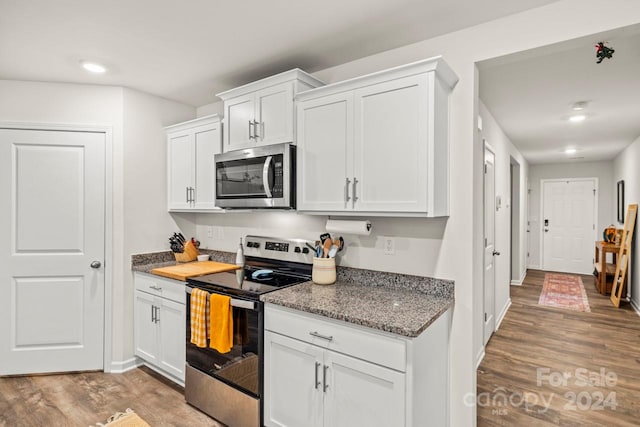 kitchen featuring dark stone countertops, white cabinetry, appliances with stainless steel finishes, and light hardwood / wood-style flooring