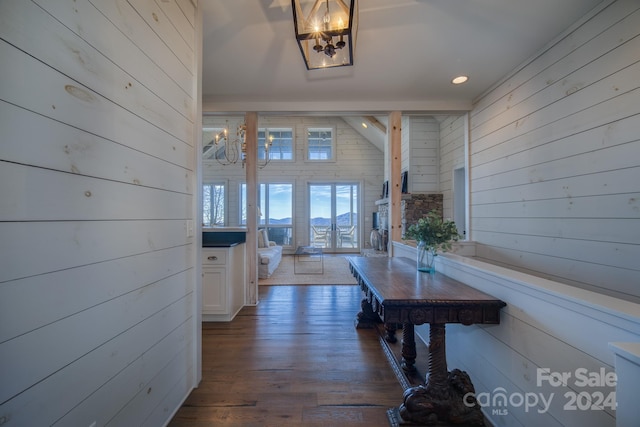 hallway with wooden walls, dark hardwood / wood-style floors, and an inviting chandelier