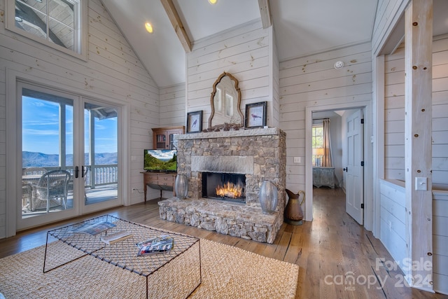 living room with a wealth of natural light, high vaulted ceiling, light hardwood / wood-style floors, and wood walls