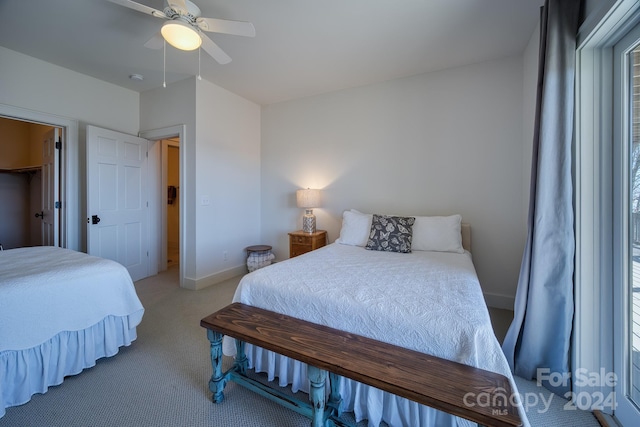 bedroom with light carpet, a walk in closet, a closet, and ceiling fan