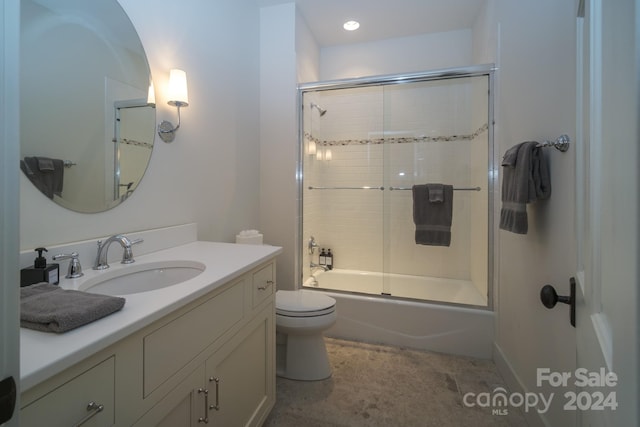 full bathroom featuring vanity, bath / shower combo with glass door, and toilet