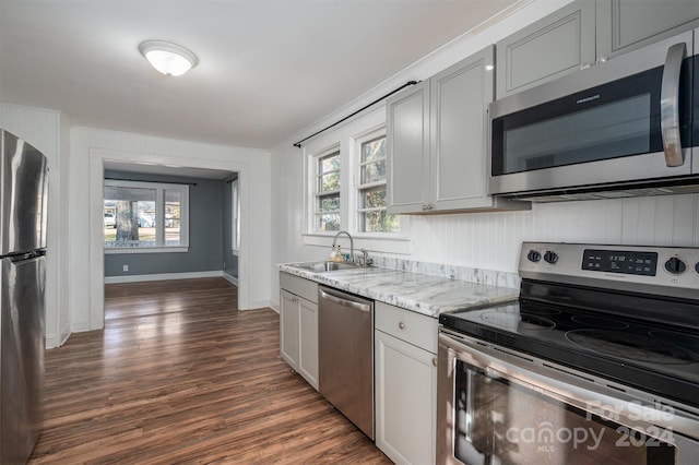 kitchen with light stone countertops, sink, dark wood-type flooring, stainless steel appliances, and gray cabinets