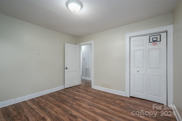 unfurnished bedroom with a closet and dark hardwood / wood-style floors