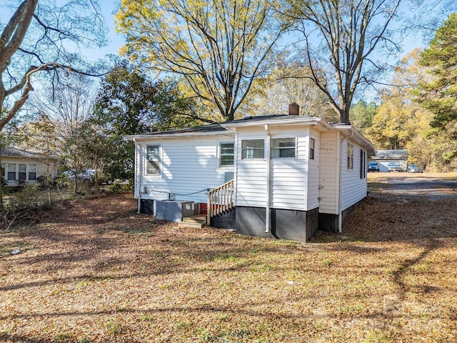 rear view of property featuring a lawn and cooling unit