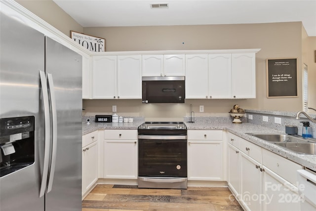 kitchen with light stone countertops, appliances with stainless steel finishes, sink, light hardwood / wood-style flooring, and white cabinets