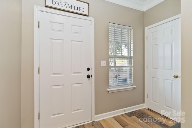 foyer entrance featuring ornamental molding, light wood-style flooring, and baseboards