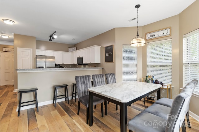 dining space with rail lighting, visible vents, light wood-style flooring, and baseboards