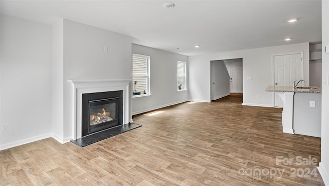 unfurnished living room with light wood-type flooring and sink