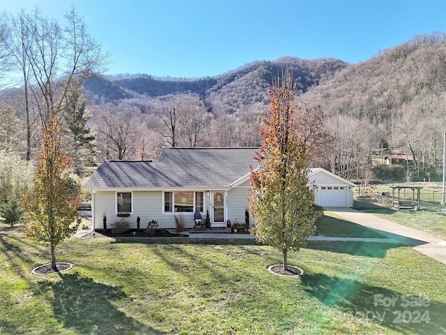 ranch-style home with a mountain view, a garage, an outbuilding, and a front lawn