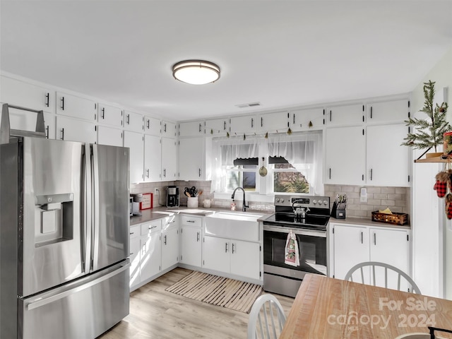 kitchen featuring sink, stainless steel appliances, tasteful backsplash, light hardwood / wood-style flooring, and white cabinets