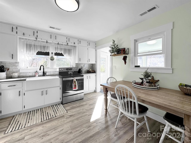 kitchen featuring white cabinetry, sink, tasteful backsplash, light hardwood / wood-style flooring, and electric stove