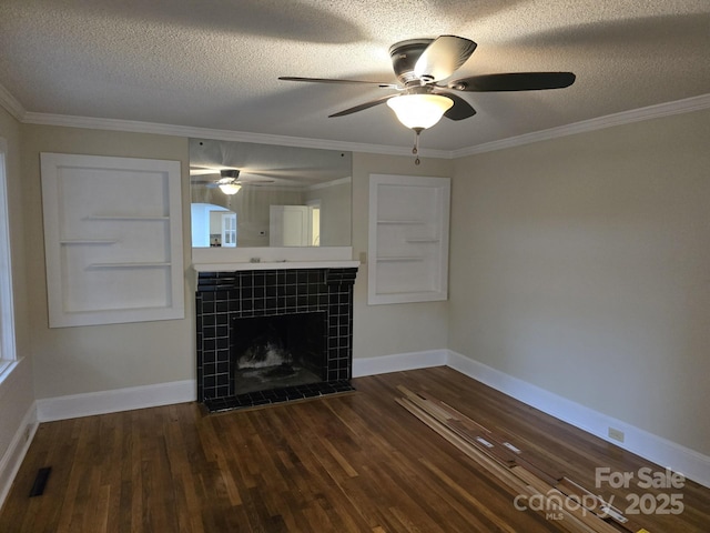 unfurnished living room with a textured ceiling, dark hardwood / wood-style flooring, crown molding, and a tiled fireplace