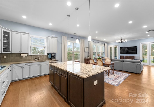 kitchen with backsplash, white cabinetry, light wood-type flooring, and hanging light fixtures